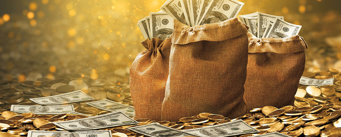 Three burlap bags overflow with paper currency and sit among scattered bills and gold coins
