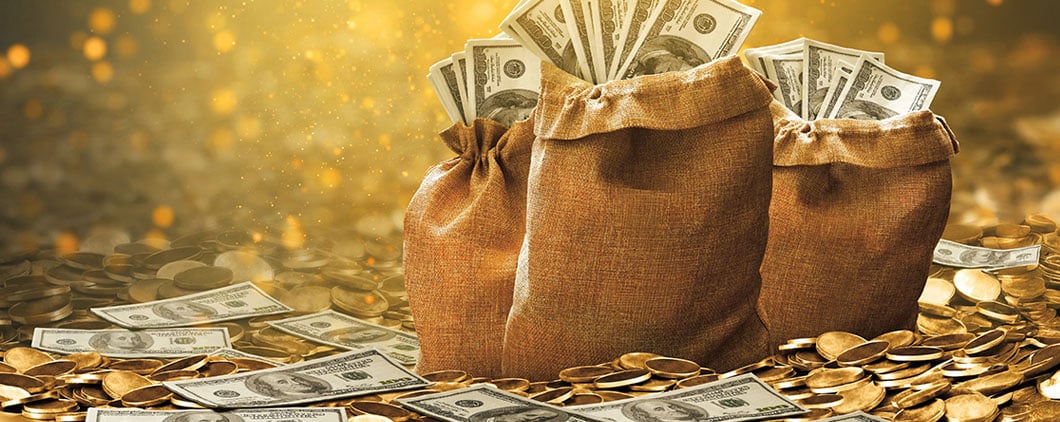 Three burlap bags filled with cash sit among scattered bills and gold coins