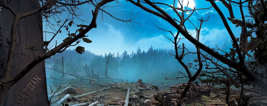 A moonlit forest clearing covered in fallen logs and bare trees with the word Croatoan carved into a trunk