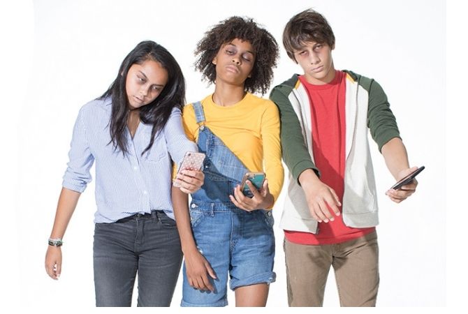 three teens looking down at their phones while posed as zombies